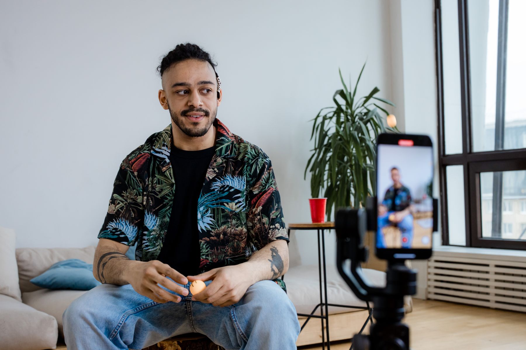 A male creator filming a video on his mounted iPhone at home